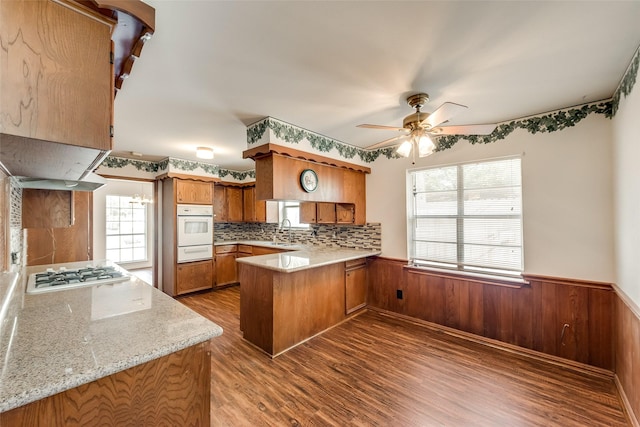 6310 Ash Oak Dr, Houston, TX 77091 - kitchen with a warming drawer, a peninsula, white oven, brown cabinetry, and a sink