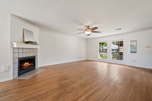 4309 Kingfish Dr, Seabrook, TX 77586 - unfurnished living room featuring wood finished floors, a textured ceiling, ceiling fan, a fireplace, and ornamental molding