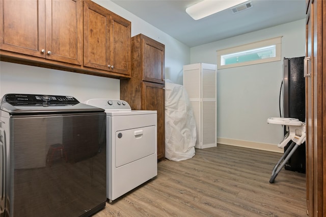2585 Tide Dr, Crystal Beach, TX 77650 - laundry area with cabinet space, independent washer and dryer, light wood finished floors, and baseboards