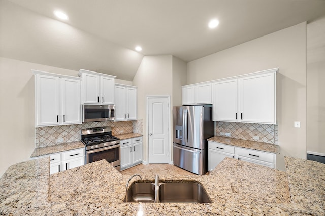 19119 Cardinal Grove Ct, Cypress, TX 77429 - kitchen featuring appliances with stainless steel finishes, decorative backsplash, white cabinetry, light stone countertops, and vaulted ceiling