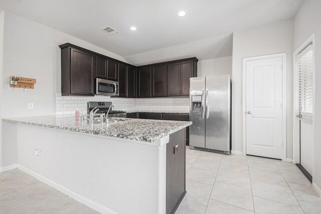 607 Harvest Bluff Dr, Rosharon, TX 77583 - kitchen with appliances with stainless steel finishes, backsplash, light stone counters, a peninsula, and dark brown cabinets
