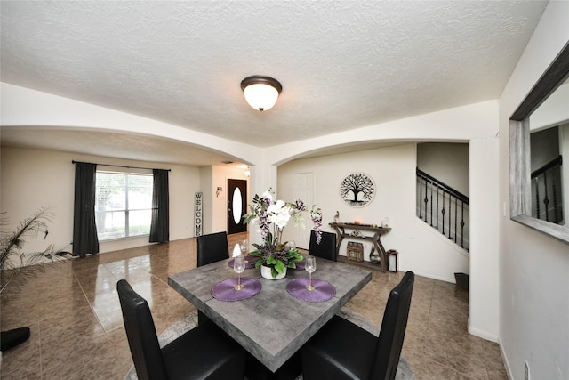 9107 S Ferndale Place Dr, Houston, TX 77064 - dining space with arched walkways, stairway, a textured ceiling, and tile patterned flooring