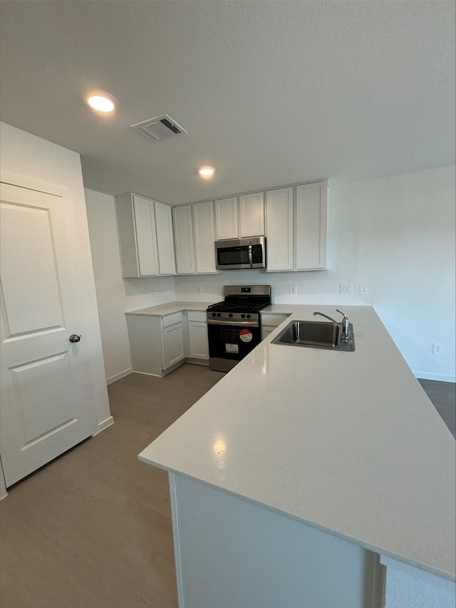 3074 Mallorca Dr, Conroe, TX 77301 - kitchen featuring appliances with stainless steel finishes, a sink, a peninsula, white cabinets, and recessed lighting