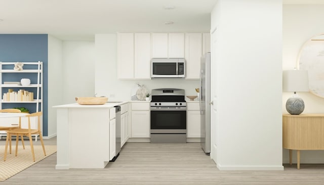 3074 Mallorca Dr, Conroe, TX 77301 - kitchen featuring stainless steel appliances, light wood-style flooring, white cabinets, and a peninsula