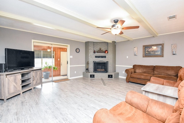 466 Emanuel Rd, Goodrich, TX 77335 - living room featuring beam ceiling, a ceiling fan, ornamental molding, light wood-style flooring, and a brick fireplace