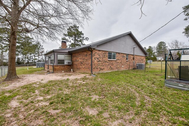 466 Emanuel Rd, Goodrich, TX 77335 - rear view of house featuring brick siding, a chimney, central AC, and cooling unit
