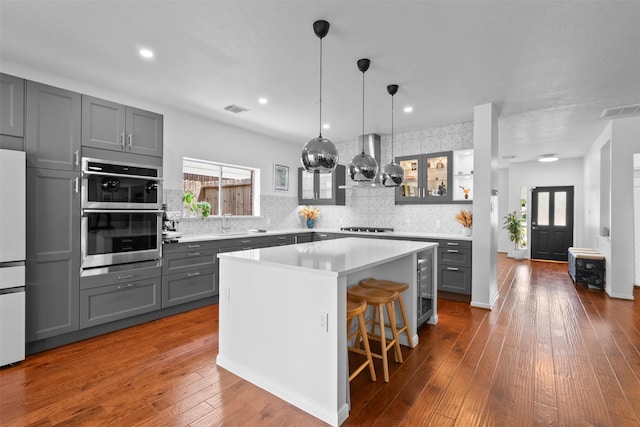 21519 Canyon Terrace Ln, Katy, TX 77450 - kitchen featuring gray cabinetry, decorative backsplash, stainless steel double oven, a kitchen island, and wine cooler
