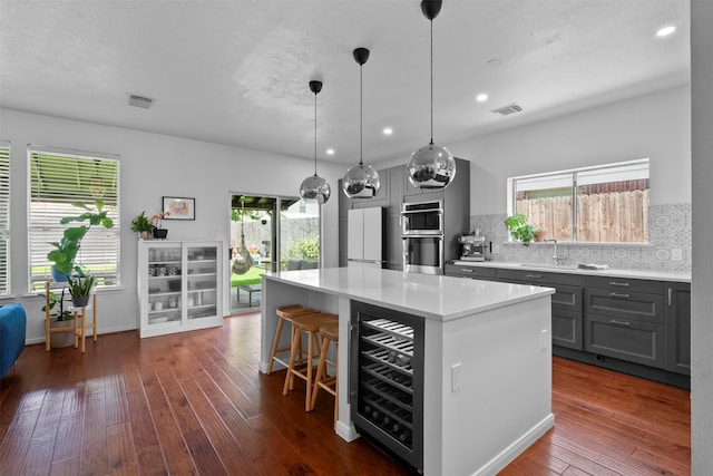 21519 Canyon Terrace Ln, Katy, TX 77450 - kitchen with beverage cooler, stainless steel double oven, a center island, backsplash, and a breakfast bar