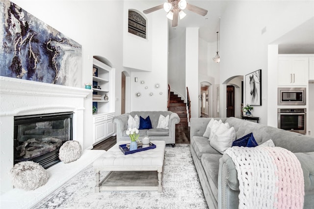 21622 Sabine Pass Ct, Katy, TX 77450 - living room with high vaulted ceiling, arched walkways, stairs, a ceiling fan, and a glass covered fireplace