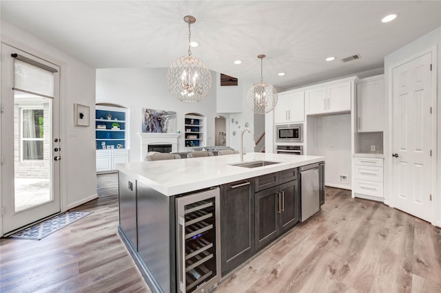 21622 Sabine Pass Ct, Katy, TX 77450 - kitchen featuring wine cooler, stainless steel appliances, white cabinets, a fireplace, and light countertops