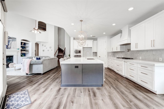 21622 Sabine Pass Ct, Katy, TX 77450 - kitchen featuring premium range hood, open floor plan, recessed lighting, a glass covered fireplace, and white cabinetry