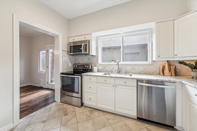 701 Bering Dr Unit 1702, Houston, TX 77057 - kitchen featuring appliances with stainless steel finishes, a sink, backsplash, white cabinets, and light stone counters