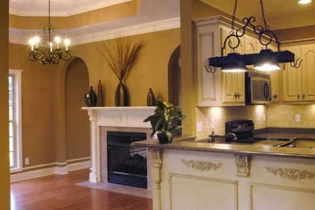 301 Live Oak St, Gonzales, TX 78629 - kitchen featuring stainless steel microwave, a chandelier, dark wood finished floors, arched walkways, and a fireplace