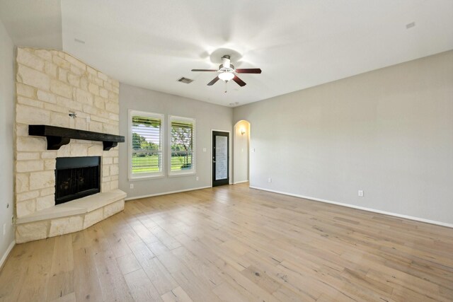 10315 Silver Shield Way, Tomball, TX 77375 - unfurnished living room featuring ceiling fan, baseboards, light wood-style flooring, a fireplace, and arched walkways