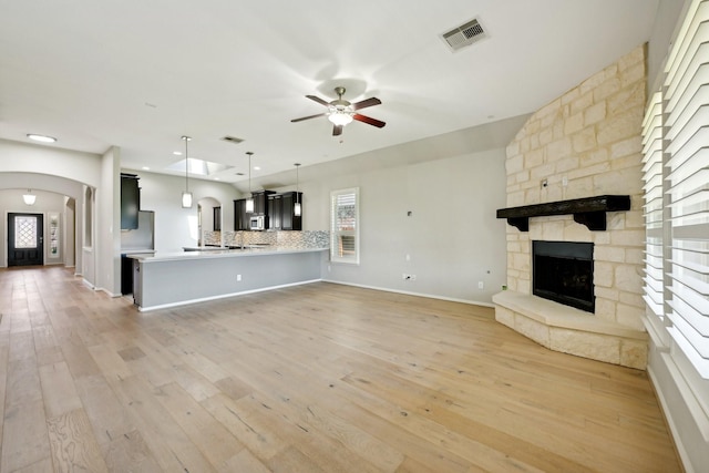 10315 Silver Shield Way, Tomball, TX 77375 - unfurnished living room featuring arched walkways, a fireplace, a ceiling fan, light wood-type flooring, and recessed lighting