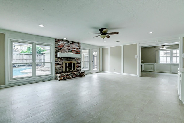 1406 Rustic Knolls Dr, Katy, TX 77450 - unfurnished living room featuring ceiling fan, a decorative wall, a fireplace, recessed lighting, and a textured ceiling