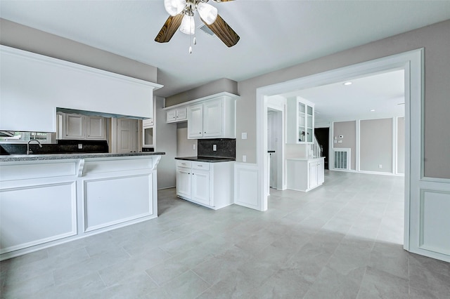 1406 Rustic Knolls Dr, Katy, TX 77450 - kitchen with a ceiling fan, dark countertops, decorative backsplash, and white cabinetry
