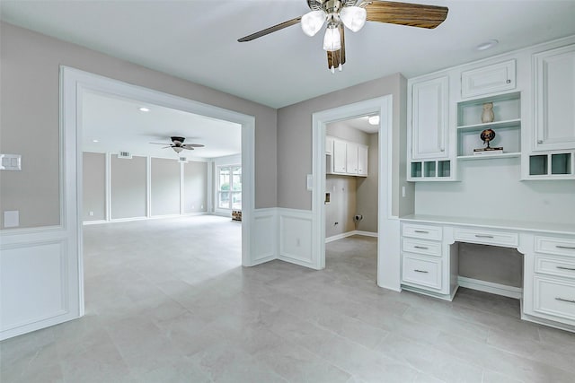 1406 Rustic Knolls Dr, Katy, TX 77450 - unfurnished office featuring ceiling fan, built in desk, wainscoting, and a decorative wall