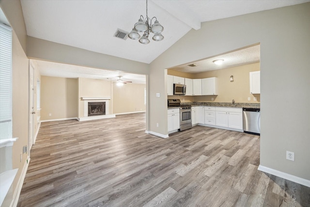 4446 Castor St, Houston, TX 77022 - kitchen with stainless steel appliances, white cabinetry, light wood finished floors, open floor plan, and a chandelier