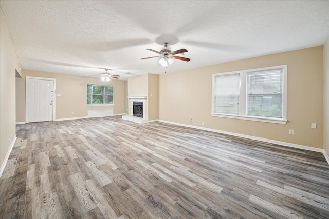 4446 Castor St, Houston, TX 77022 - unfurnished living room featuring a textured ceiling, wood finished floors, a ceiling fan, baseboards, and a fireplace with raised hearth