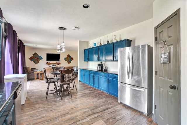 6706 Lindale Manor Ct, Spring, TX 77379 - kitchen featuring freestanding refrigerator, blue cabinets, wood finished floors, a ceiling fan, and hanging light fixtures
