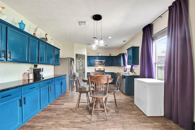 6706 Lindale Manor Ct, Spring, TX 77379 - kitchen with stainless steel appliances, blue cabinets, light wood-type flooring, and decorative light fixtures
