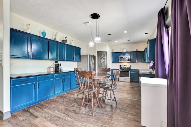 6706 Lindale Manor Ct, Spring, TX 77379 - kitchen with stainless steel appliances, blue cabinets, wood finished floors, decorative light fixtures, and recessed lighting