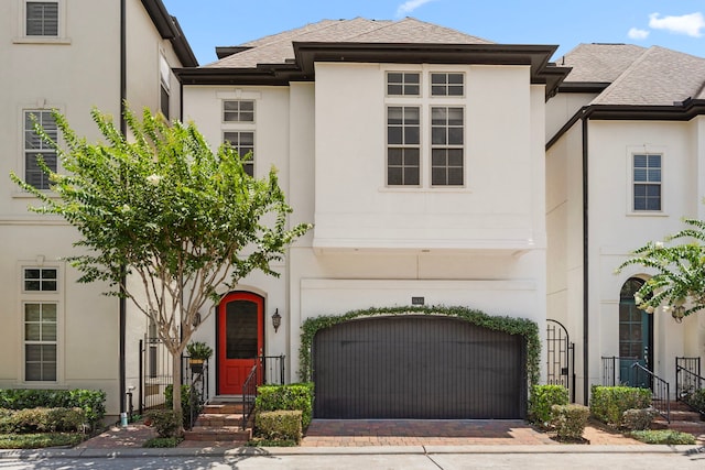 1616 Wrenwood Lks, Houston, TX 77043 - view of front facade featuring a garage, stucco siding, decorative driveway, and a shingled roof