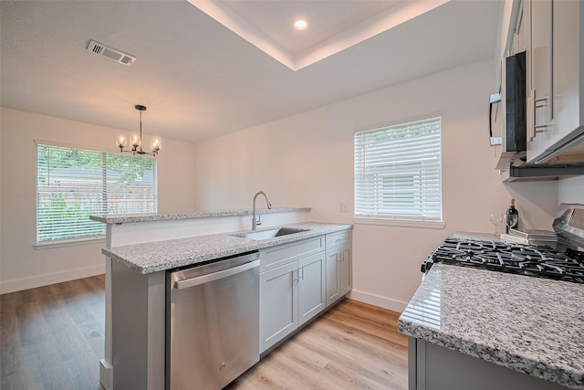 19803 Packwood Dr, Katy, TX 77449 - kitchen featuring stainless steel appliances, a peninsula, a chandelier, and light wood-style floors