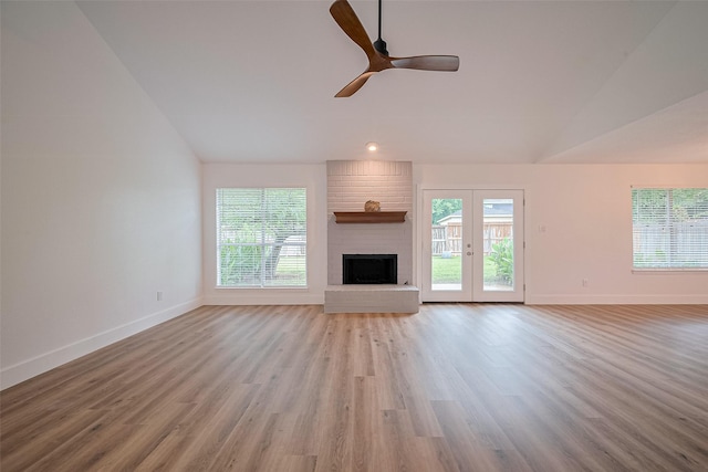 19803 Packwood Dr, Katy, TX 77449 - unfurnished living room with vaulted ceiling, plenty of natural light, a brick fireplace, wood finished floors, and french doors