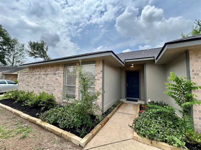 19803 Packwood Dr, Katy, TX 77449 - view of exterior entry featuring brick siding and a shingled roof