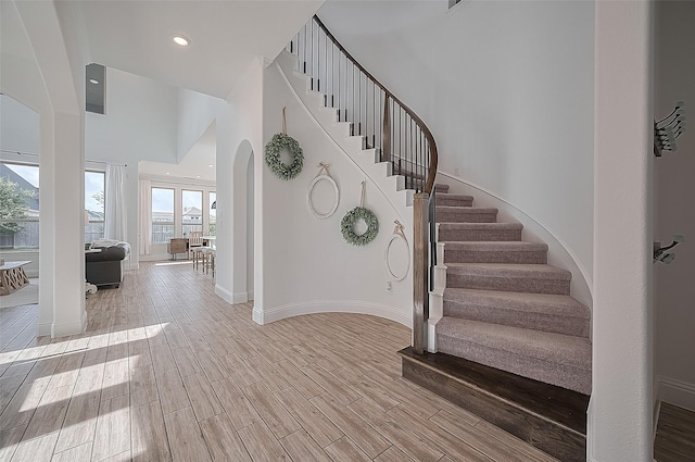 18003 Winding Willow Oak Way, Cypress, TX 77433 - staircase featuring wood finished floors, arched walkways, recessed lighting, and a high ceiling