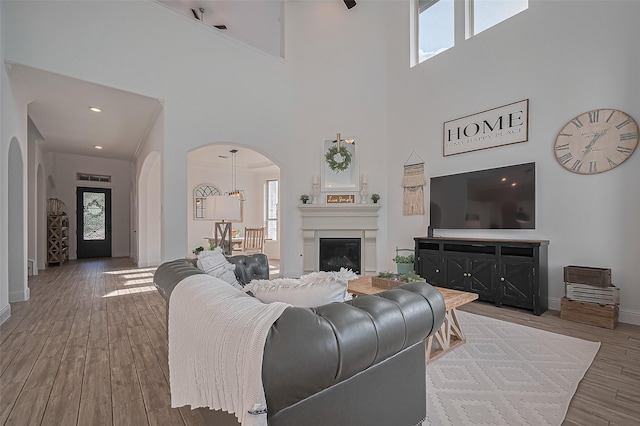 18003 Winding Willow Oak Way, Cypress, TX 77433 - living area with plenty of natural light, arched walkways, a towering ceiling, wood finished floors, and a glass covered fireplace