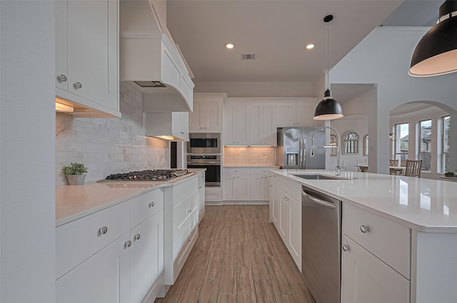 18003 Winding Willow Oak Way, Cypress, TX 77433 - kitchen featuring appliances with stainless steel finishes, arched walkways, light countertops, premium range hood, and white cabinets