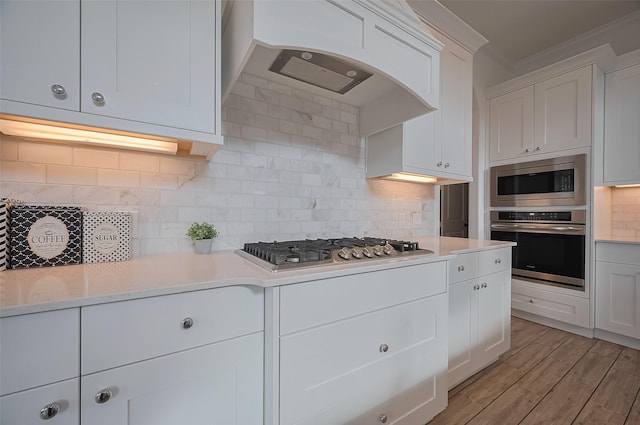 18003 Winding Willow Oak Way, Cypress, TX 77433 - kitchen featuring appliances with stainless steel finishes, crown molding, light countertops, white cabinets, and extractor fan