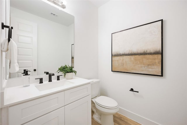 5322 Rue St, Houston, TX 77033 - bathroom featuring vanity, toilet, wood finished floors, and baseboards