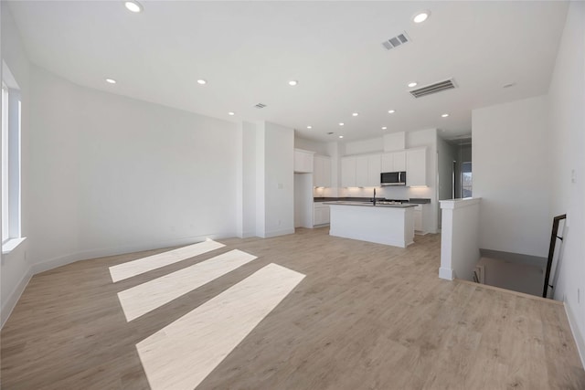 5324 Rue St, Houston, TX 77033 - unfurnished living room featuring recessed lighting, light wood-style flooring, baseboards, and a sink