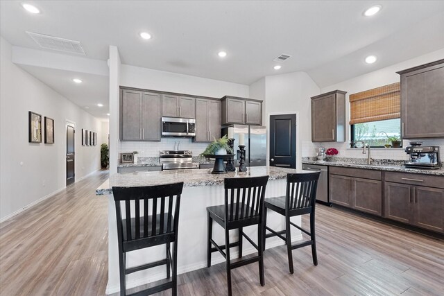 16997 White Birch Ln, Conroe, TX 77385 - kitchen with stainless steel appliances, backsplash, a sink, a kitchen breakfast bar, and dark brown cabinetry