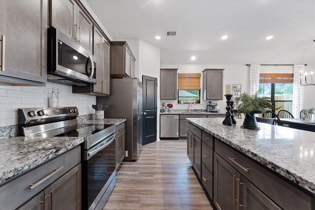 16997 White Birch Ln, Conroe, TX 77385 - kitchen featuring stainless steel appliances, light stone countertops, decorative backsplash, dark brown cabinetry, and recessed lighting