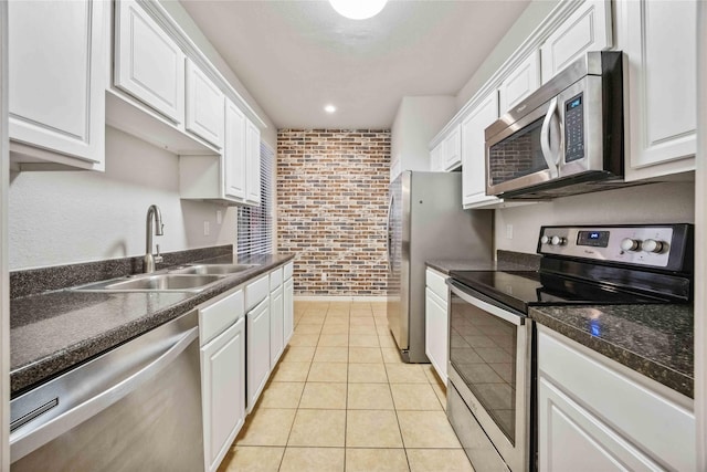 2255 Braeswood Park Dr Unit 105, Houston, TX 77030 - kitchen featuring appliances with stainless steel finishes, a sink, white cabinets, dark countertops, and brick wall