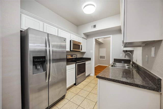 2255 Braeswood Park Dr Unit 105, Houston, TX 77030 - kitchen featuring stainless steel appliances, a sink, white cabinetry, and light tile patterned floors