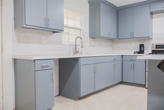 1007 Prune St, La Marque, TX 77568 - kitchen featuring gray cabinetry, light countertops, decorative backsplash, and a sink
