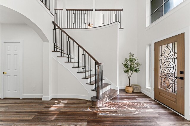 31318 Bearing Star Ln, Tomball, TX 77375 - foyer entrance with arched walkways, a high ceiling, wood finished floors, stairs, and baseboards