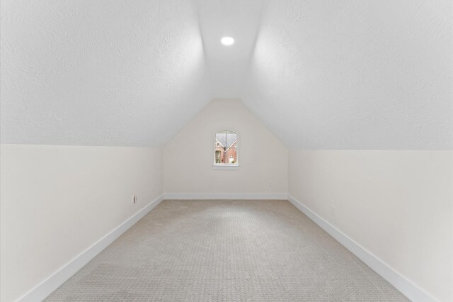 31318 Bearing Star Ln, Tomball, TX 77375 - additional living space with vaulted ceiling, baseboards, light colored carpet, and a textured ceiling