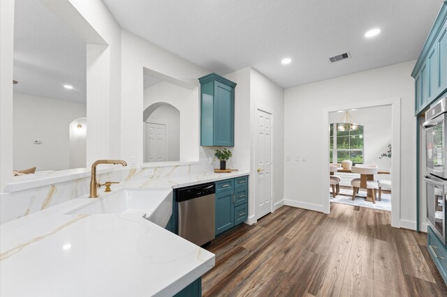 31318 Bearing Star Ln, Tomball, TX 77375 - kitchen featuring appliances with stainless steel finishes, dark wood-type flooring, a sink, blue cabinets, and light stone countertops