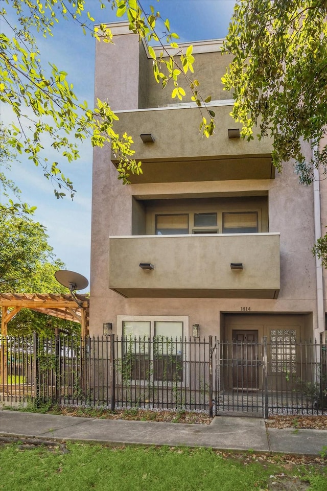 1814 Rosalie St, Houston, TX 77004 - rear view of house featuring a fenced front yard, stucco siding, and a balcony