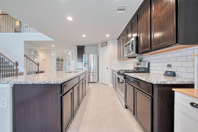 3415 Sicily Island Ln, Katy, TX 77494 - kitchen featuring stainless steel appliances, a sink, a center island with sink, dark brown cabinetry, and recessed lighting