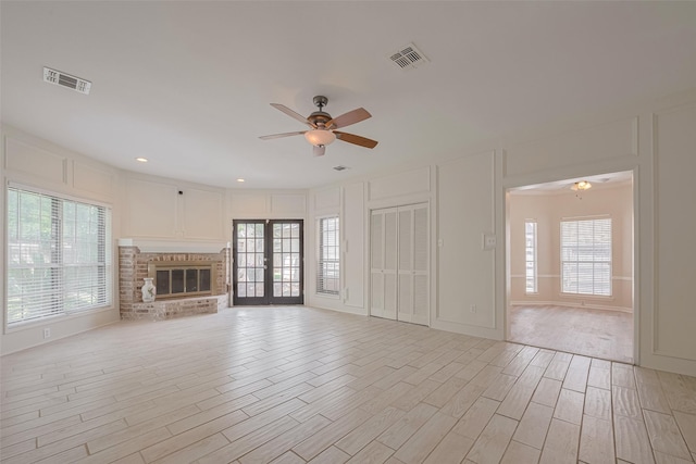 5210 Holly View Dr, Houston, TX 77091 - unfurnished living room with ceiling fan, plenty of natural light, light wood-style flooring, a brick fireplace, and a decorative wall