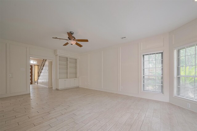5210 Holly View Dr, Houston, TX 77091 - empty room featuring a decorative wall, ceiling fan, light wood-style floors, stairs, and built in shelves