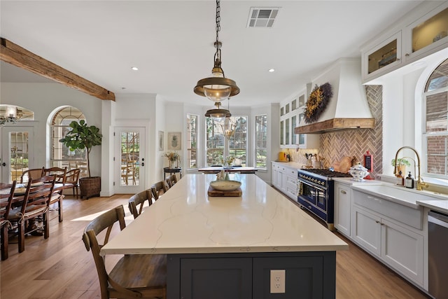 22810 Glenmont Estates Blvd, Magnolia, TX 77355 - kitchen featuring range with two ovens, premium range hood, a center island, light wood finished floors, and a sink